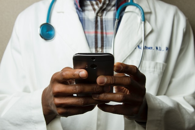 Photo of a doctor holding a phone by National Cancer Institute on Unsplash